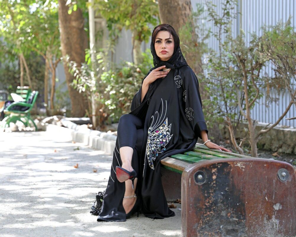 Woman in black abaya sitting on a park bench.