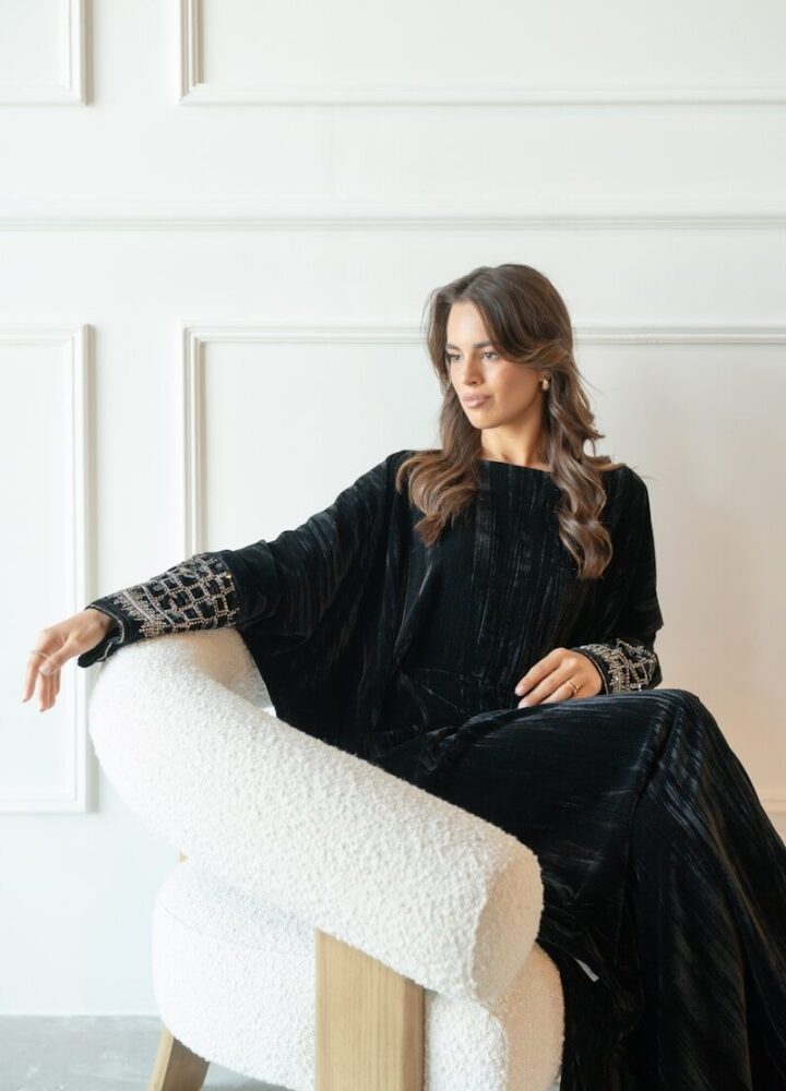 Woman in elegant black dress sitting in chair