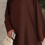 Chocolate-brown closed abaya, flowing and relaxed, finished with wide satin slit sleeves. Premium chiffon scarf included.