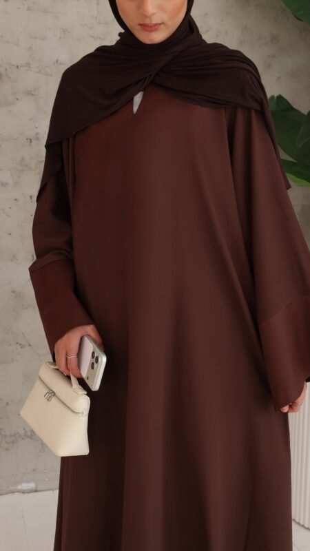 Chocolate-brown closed abaya, flowing and relaxed, finished with wide satin slit sleeves. Premium chiffon scarf included.
